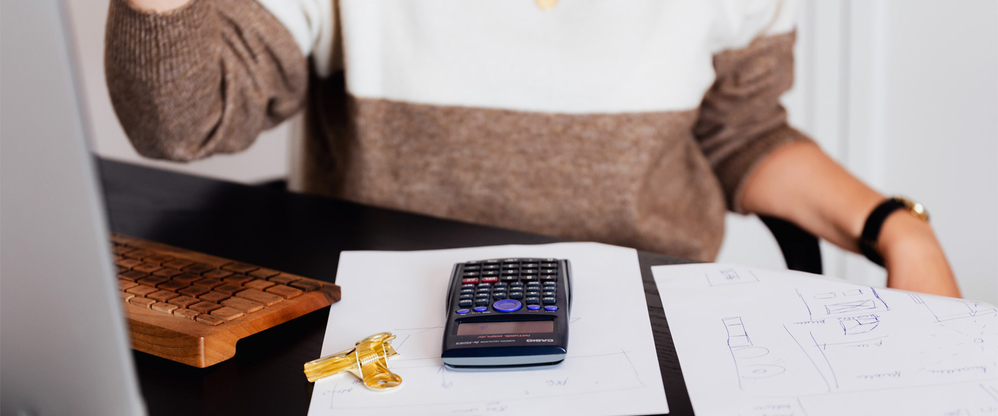 Frau am Schreibtisch. Hölzerne Tastatur, Papier und Taschenrechner auf dem Tisch.