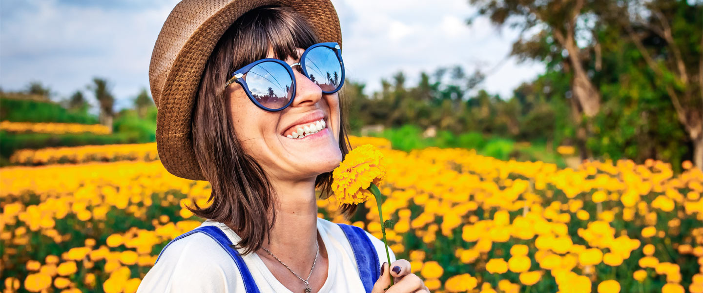 Frau steht mit Sonnenbrille in einem Blumenfeld