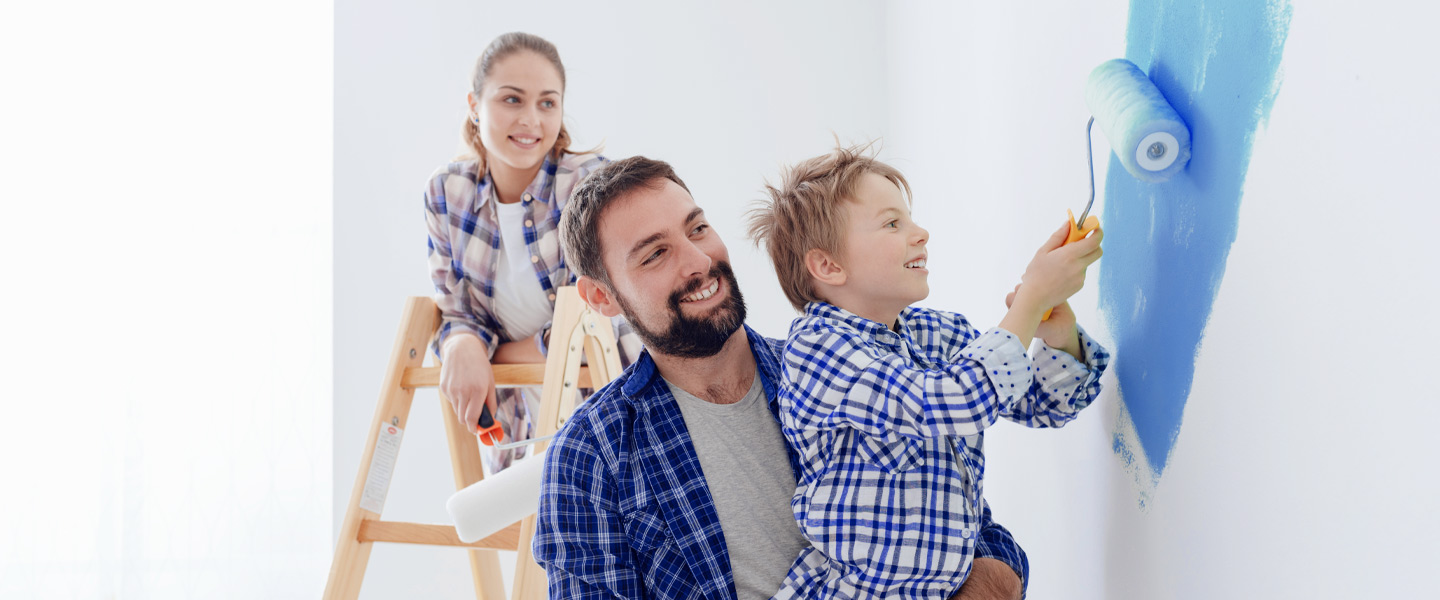 Eine junge Familie streicht zusammen ihr neues Haus.